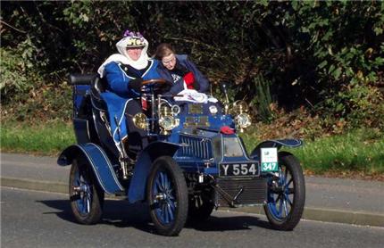 2 people in fancy dress in very old car