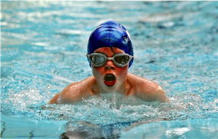 student in swimming cap and wearing goggles in pool