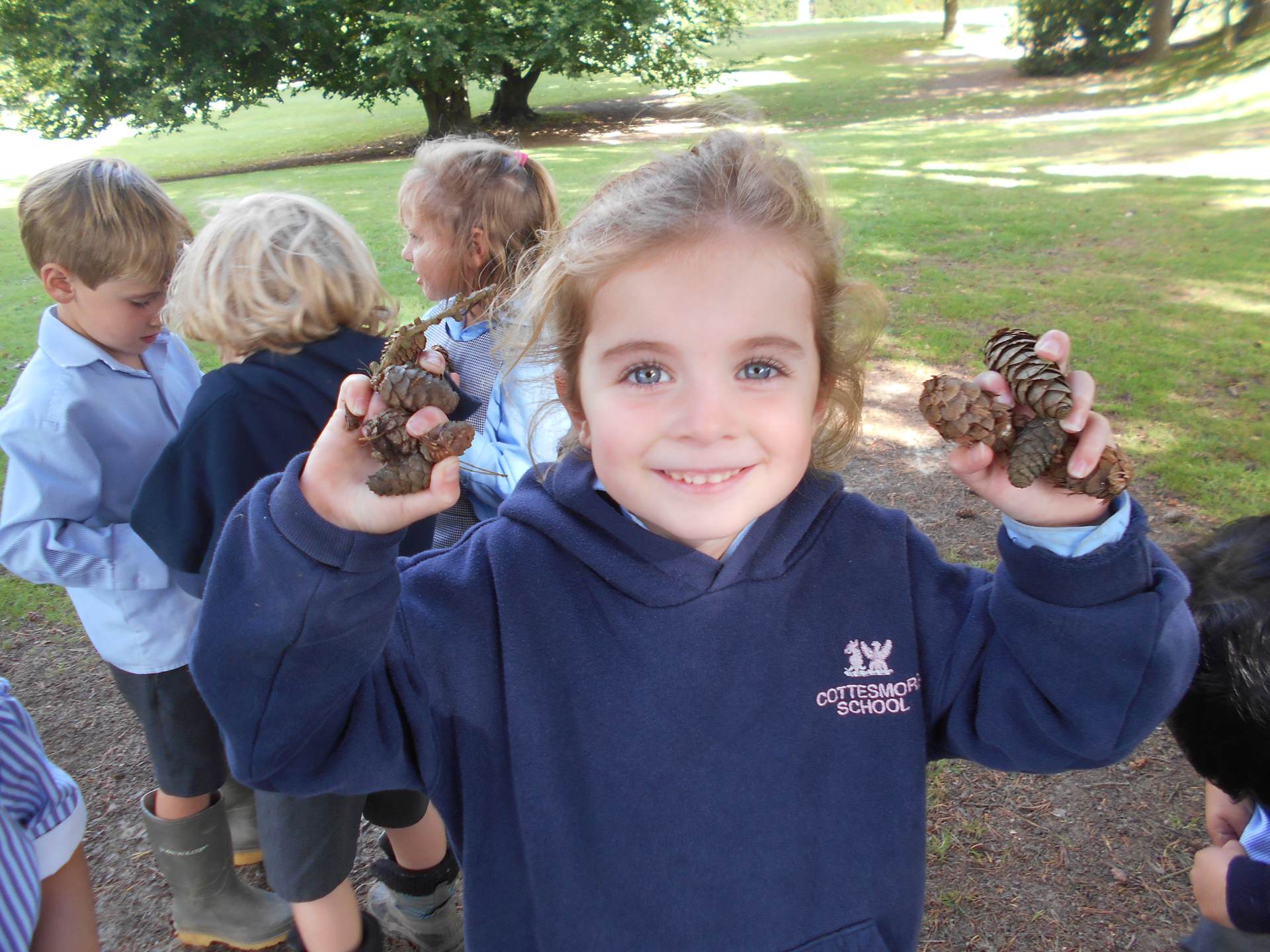 girl holding pine cones with other kids behind