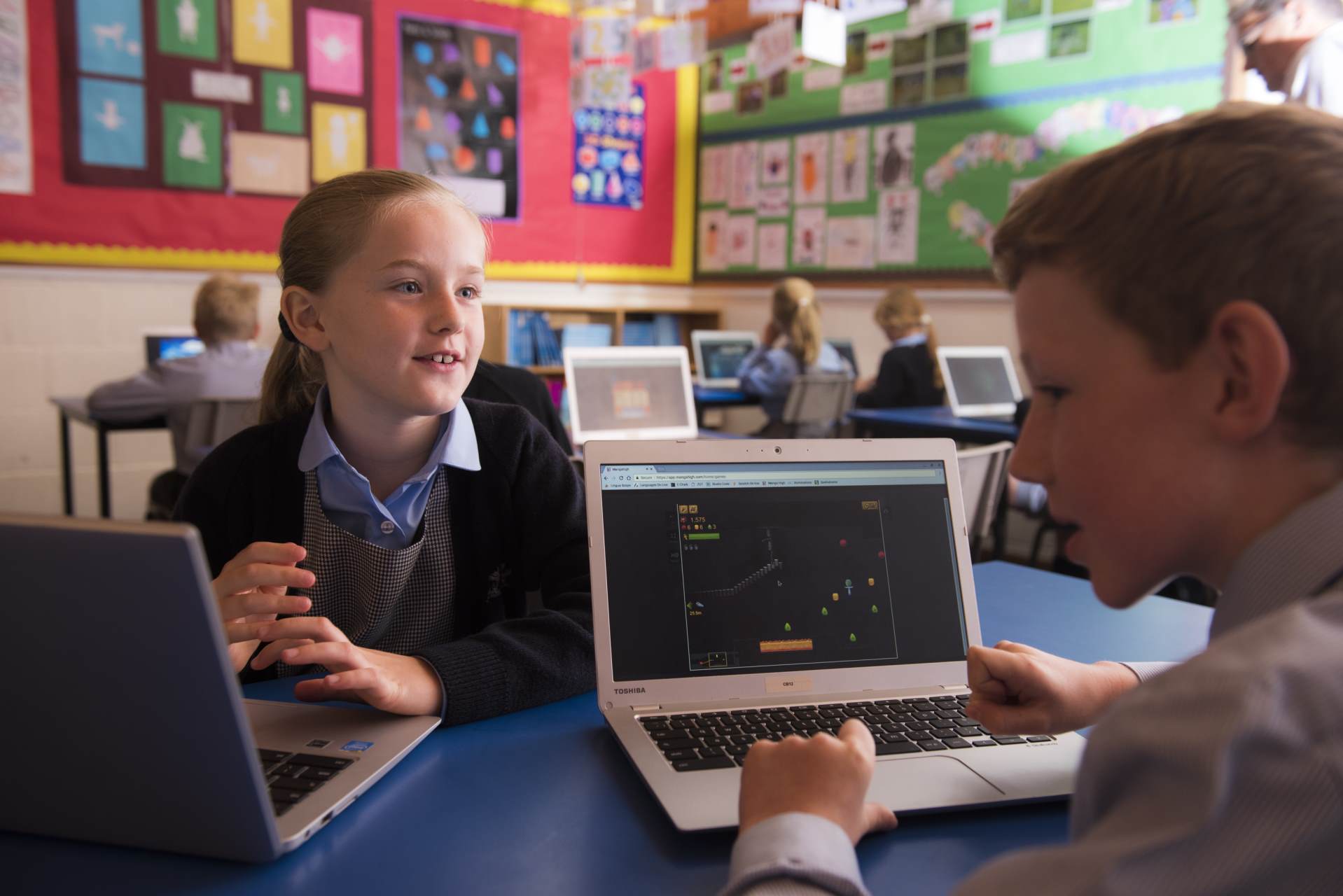 2 students working on laptops in class