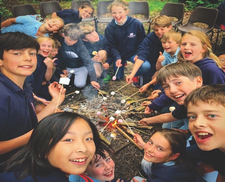 students toasting marshmallows on campfire